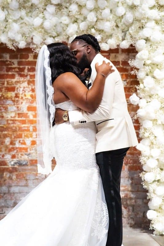 Ceremony kiss by a white floral arch