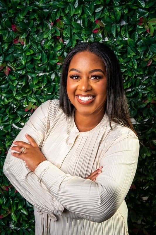 Takiea Dawkins, lead event manager, in front of a greenery wall